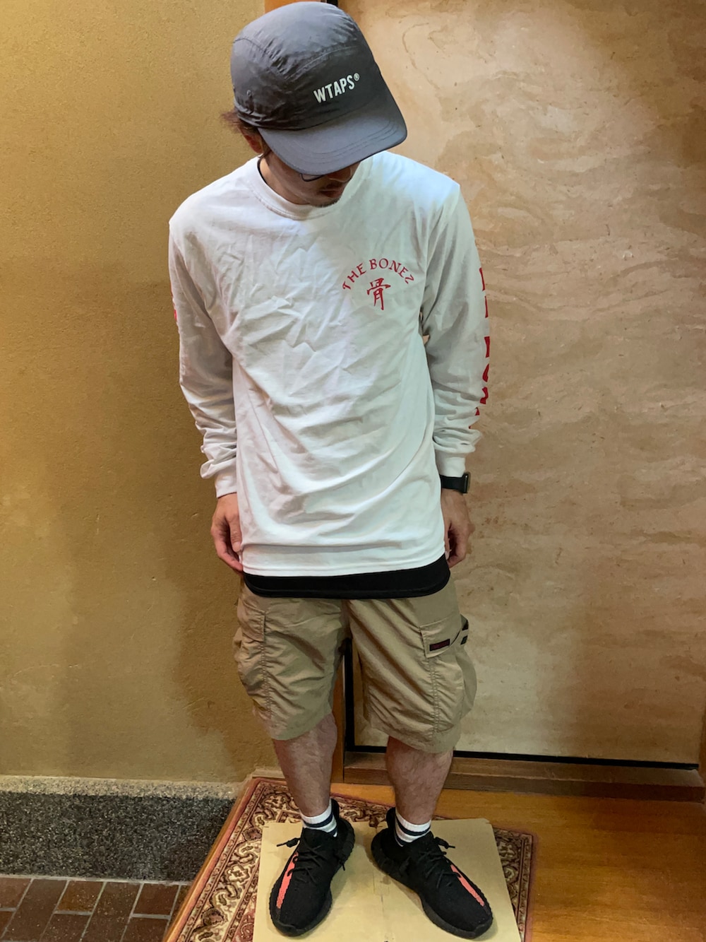 ホワイト系のTシャツ/カットソー、ベージュ系のカーゴパンツ、ブラック系のスニーカーを着用したメンズの春コーディネートの2枚目の写真