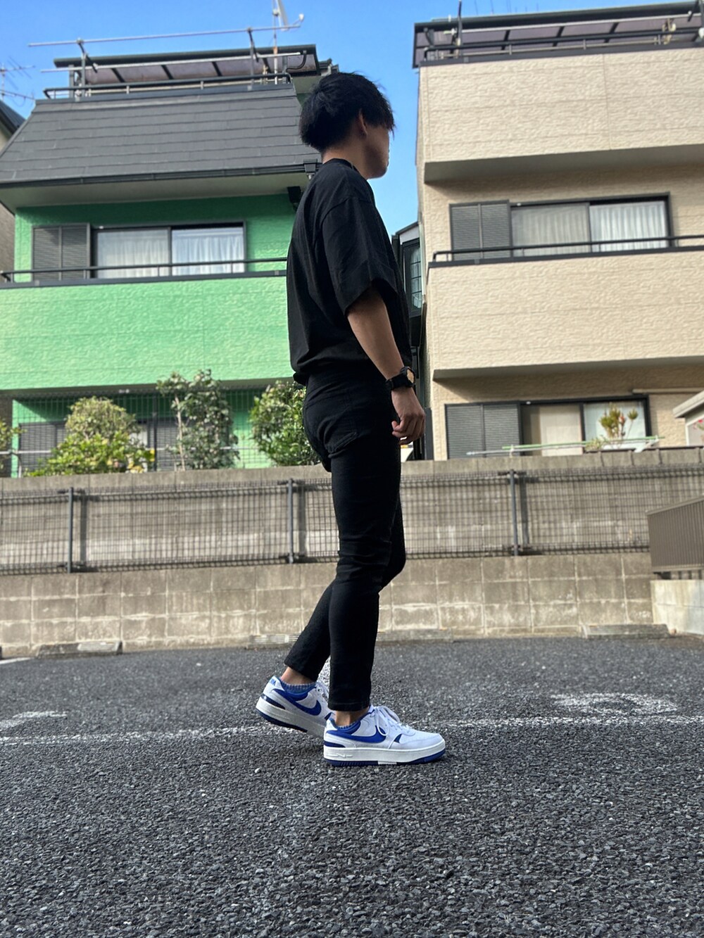ブラック系のTシャツ/カットソー、ブラック系のチノパンツ、ホワイト系のスニーカーを着用したメンズの夏コーディネートの2枚目の写真