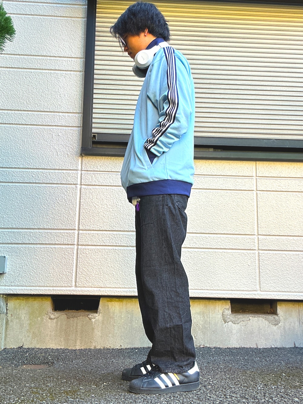 ブルー系のジャージ、ブラック系のデニムパンツ、ブラック系のスニーカーを着用したメンズの春コーディネートの2枚目の写真