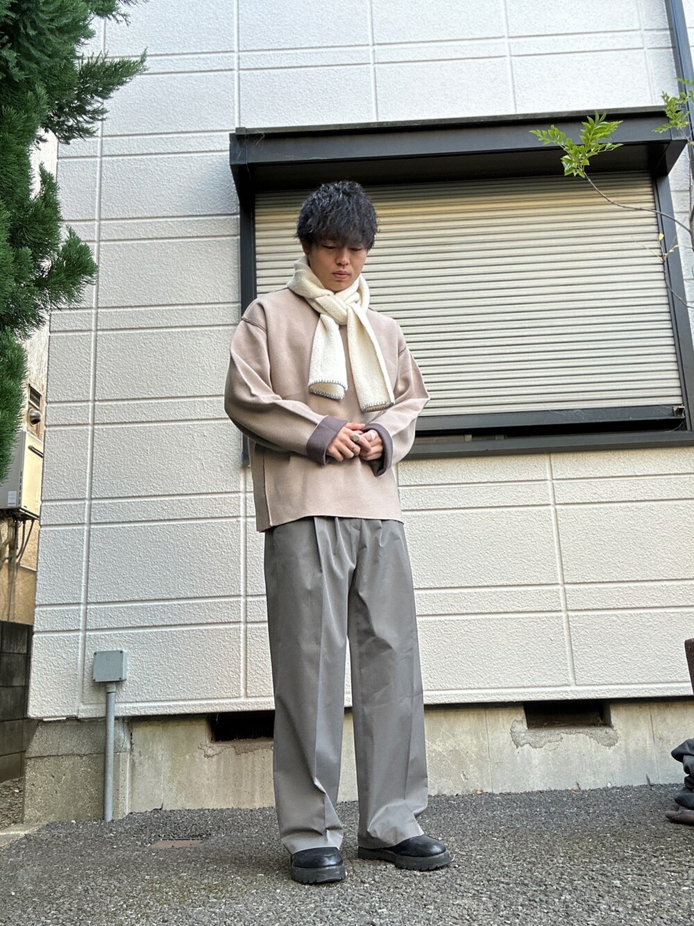 ブラウン系のチェスターコート、ベージュ系のニット/セーター、ホワイト系のニット/セーターを着用したメンズの冬コーディネートの4枚目の写真