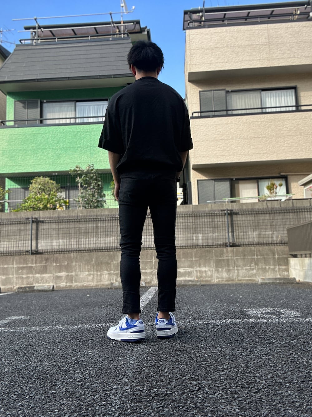 ブラック系のTシャツ/カットソー、ブラック系のチノパンツ、ホワイト系のスニーカーを着用したメンズの夏コーディネートの3枚目の写真