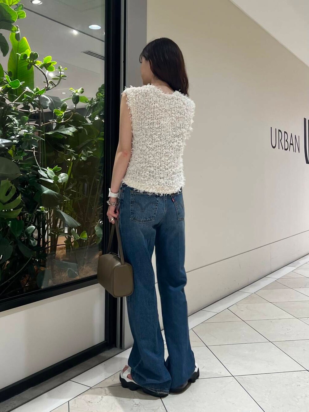 ホワイト系のサンダル、ブルー系のデニムパンツ、ベージュ系のハンドバッグを着用したレディースの夏コーディネートの4枚目の写真