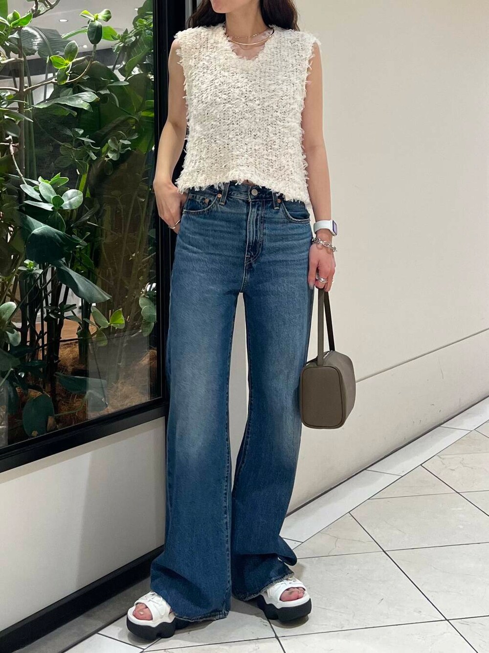 ホワイト系のサンダル、ブルー系のデニムパンツ、ベージュ系のハンドバッグを着用したレディースの夏コーディネートの2枚目の写真