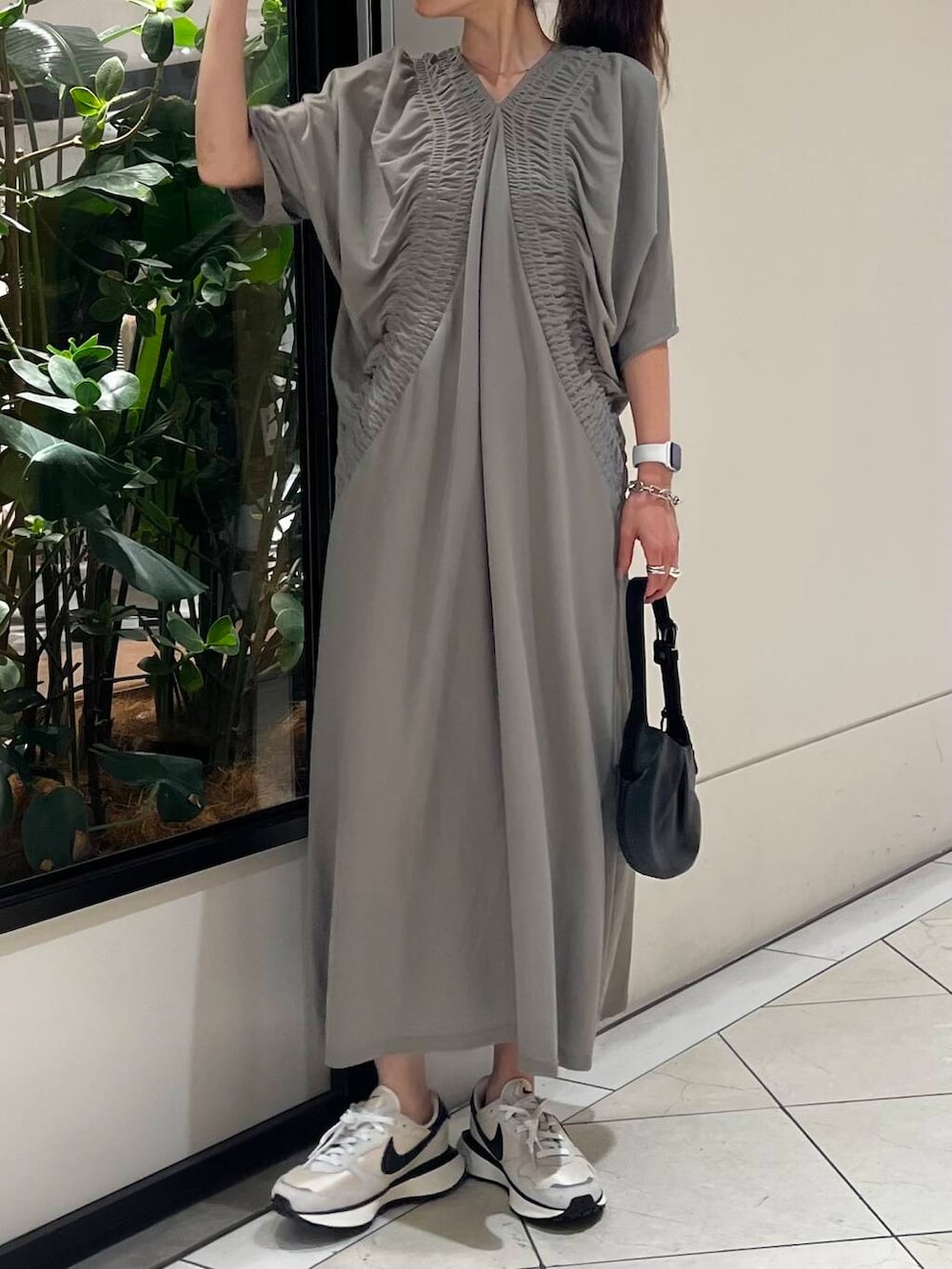 グレー系のワンピース、ホワイト系のスニーカー、ブラック系のハンドバッグを着用したレディースの夏コーディネートの2枚目の写真