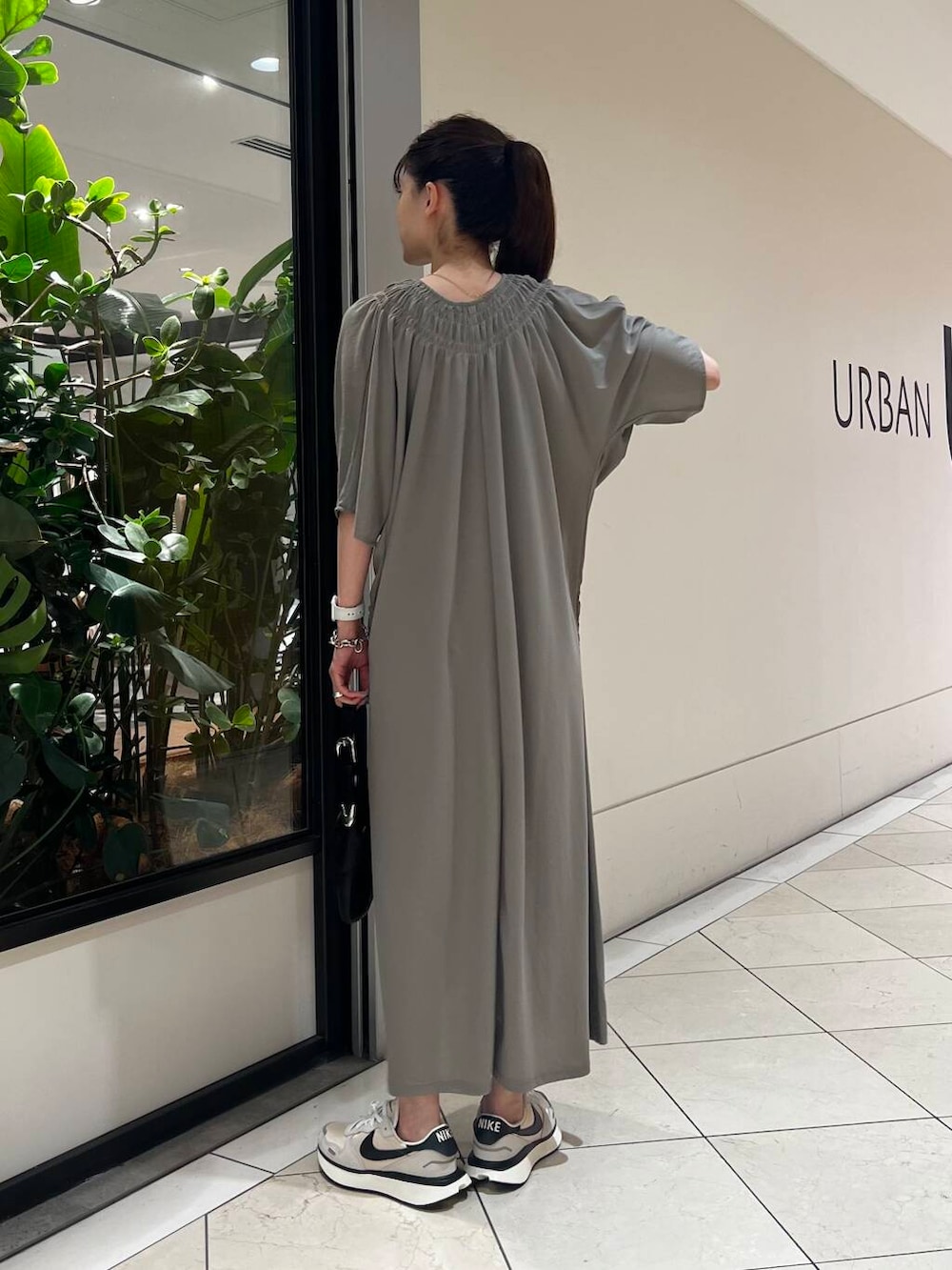 グレー系のワンピース、ホワイト系のスニーカー、ブラック系のハンドバッグを着用したレディースの夏コーディネートの4枚目の写真