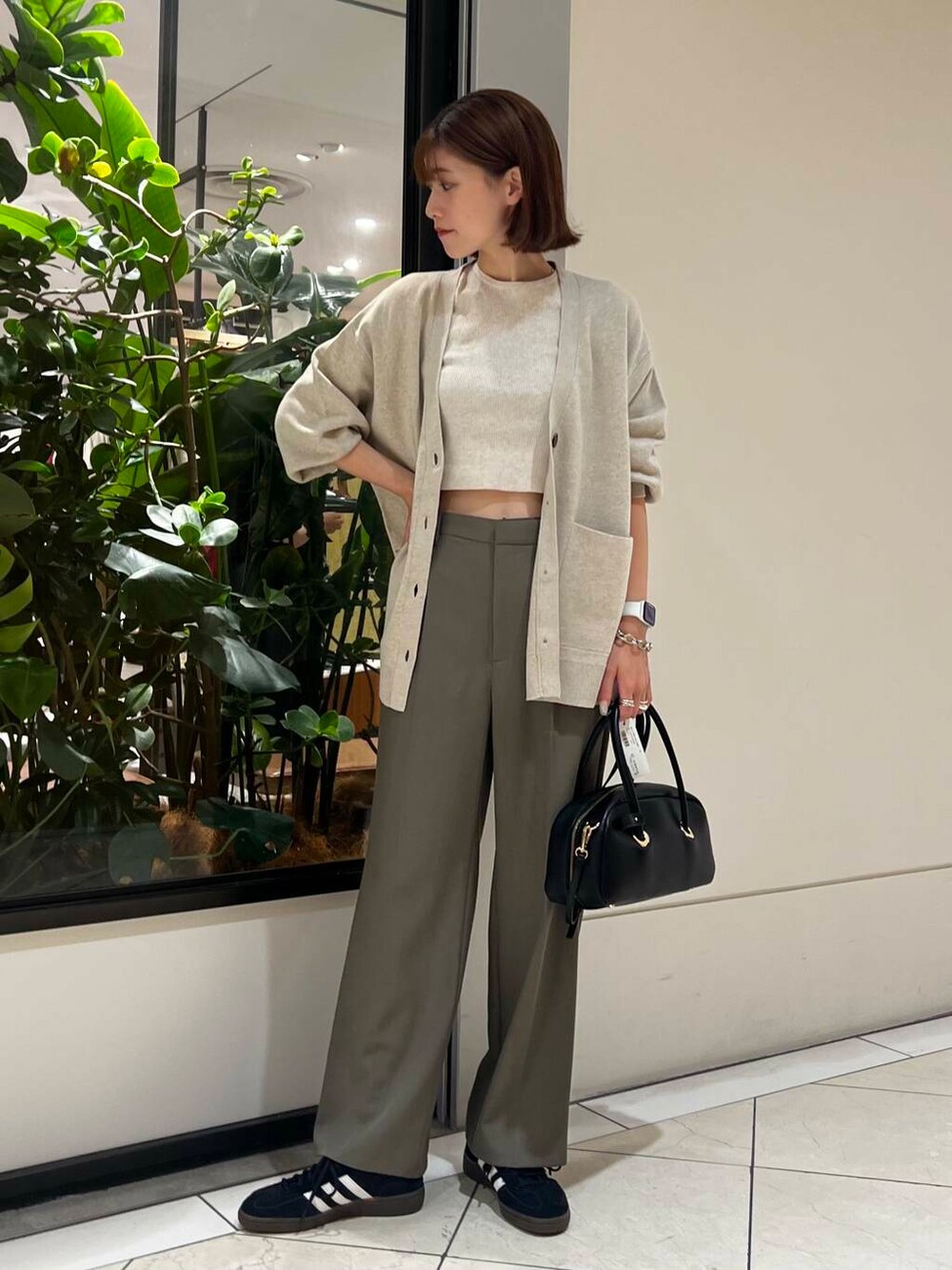 ブラック系のスニーカー、ベージュ系のカーディガン/ボレロ、ホワイト系のニット/セーターを着用したレディースの秋コーディネートの4枚目の写真