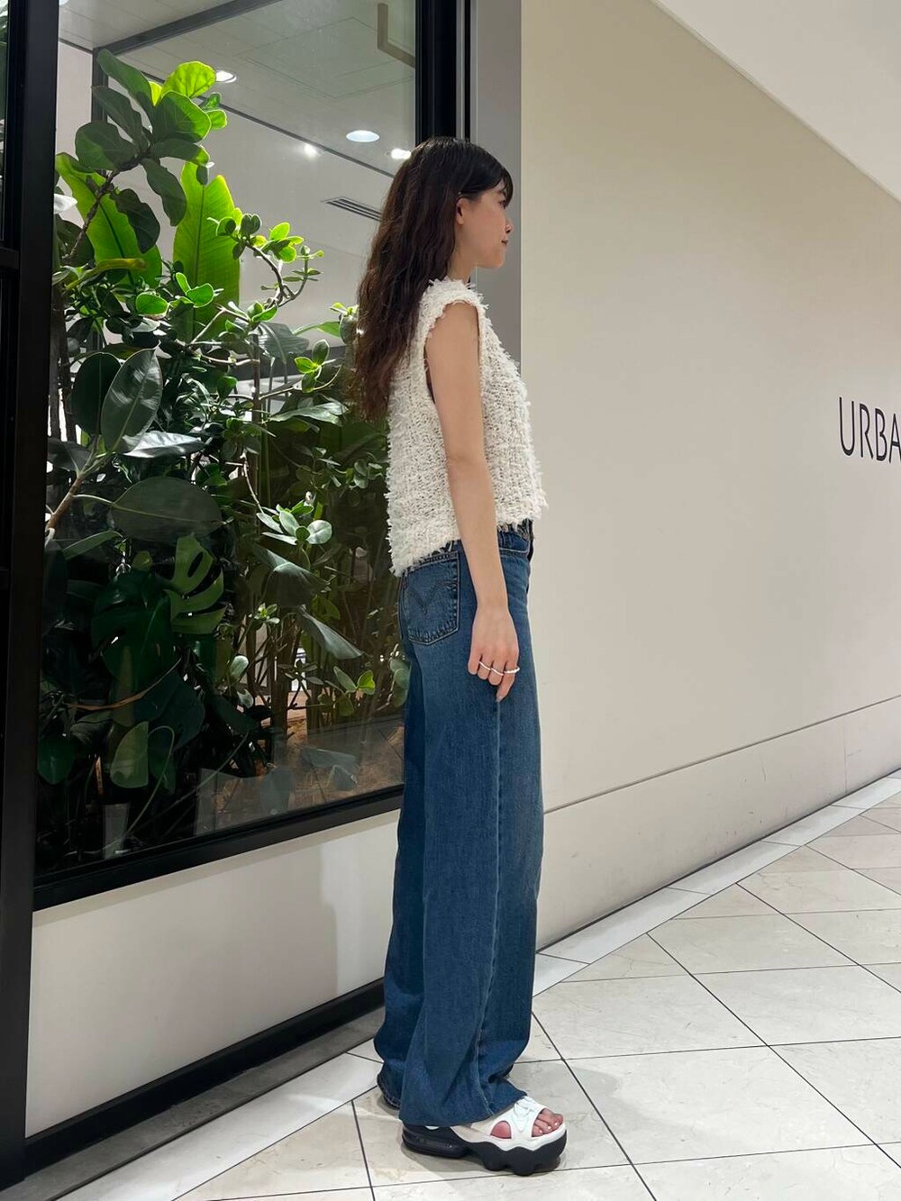 ホワイト系のサンダル、ブルー系のデニムパンツ、ベージュ系のハンドバッグを着用したレディースの夏コーディネートの3枚目の写真