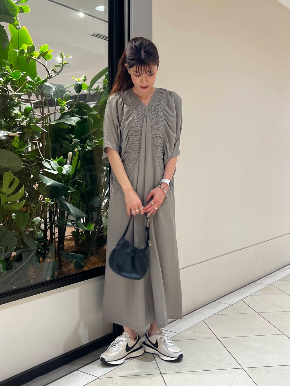 グレー系のワンピース、ホワイト系のスニーカー、ブラック系のハンドバッグを着用したレディースの夏コーディネートの5枚目の写真