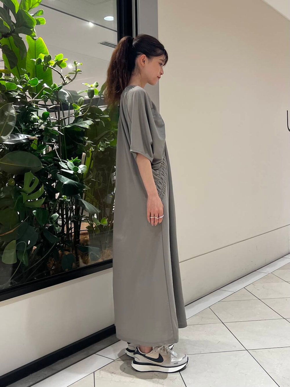 グレー系のワンピース、ホワイト系のスニーカー、ブラック系のハンドバッグを着用したレディースの夏コーディネートの3枚目の写真