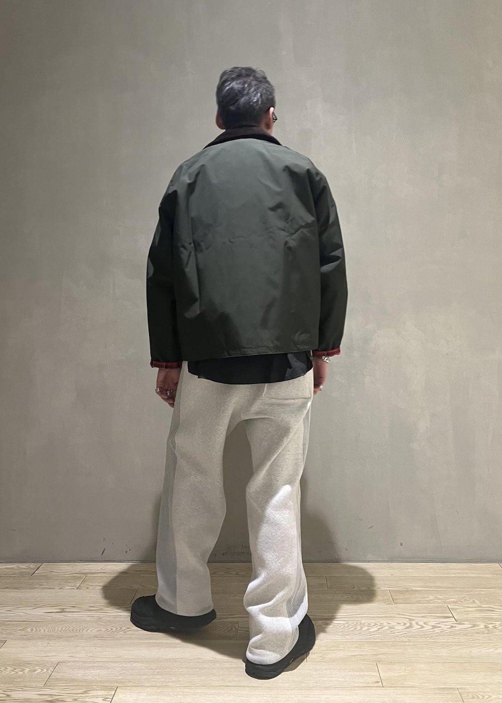 グリーン系のブルゾン、グレー系のその他パンツ、グレー系のカーディガン/ボレロを着用したメンズの冬コーディネートの3枚目の写真