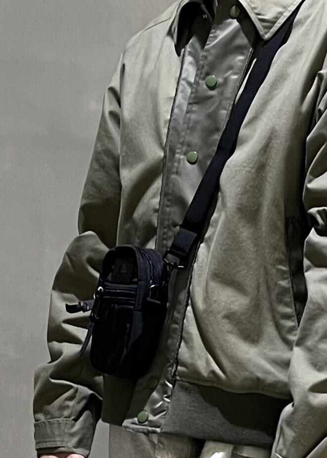 グレー系のステンカラーコート、グレー系のその他パンツ、ブラック系のショルダーバッグを着用したメンズの冬コーディネートの8枚目の写真