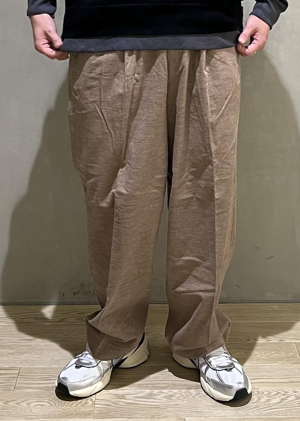 ベージュ系のスラックス、グレー系のTシャツ/カットソー、ホワイト系のスニーカーを着用したメンズの秋コーディネートの7枚目の写真