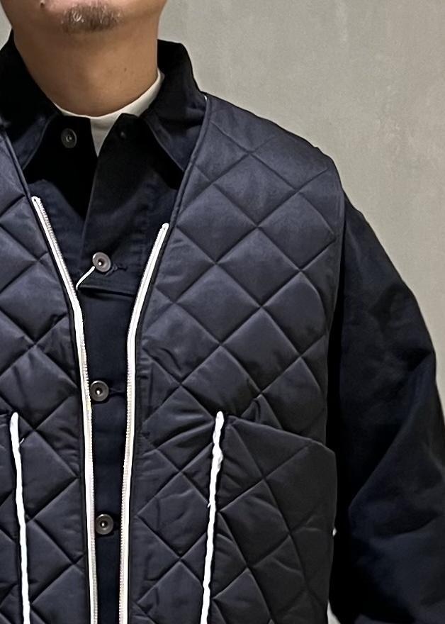 ホワイト系のスニーカー、ブラック系のその他アウター、グレー系のスラックスを着用したメンズの秋コーディネートの5枚目の写真