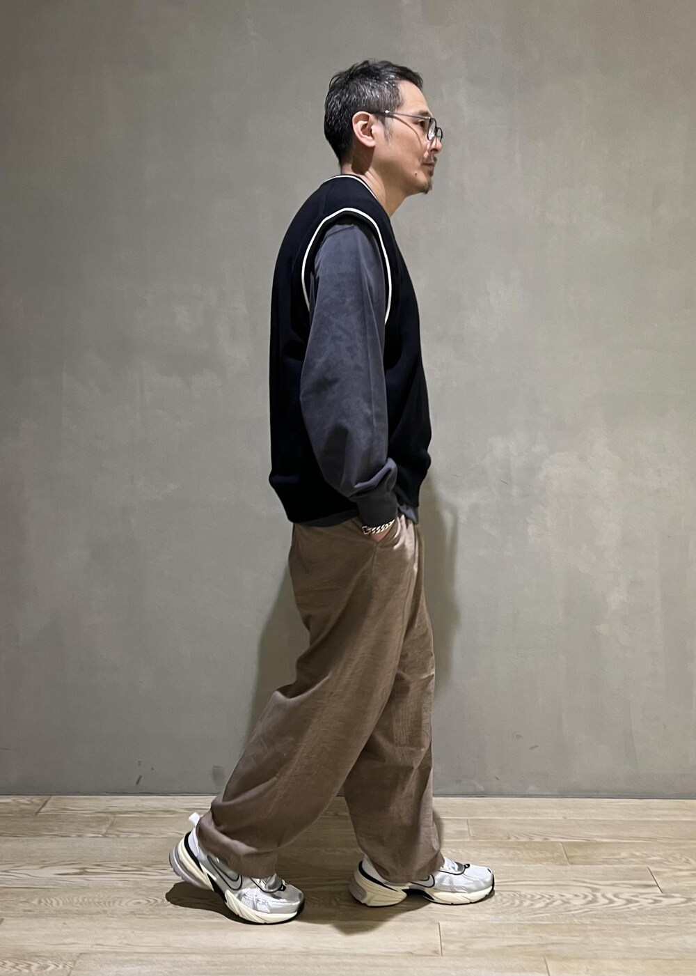 ベージュ系のスラックス、グレー系のTシャツ/カットソー、ホワイト系のスニーカーを着用したメンズの秋コーディネートの2枚目の写真