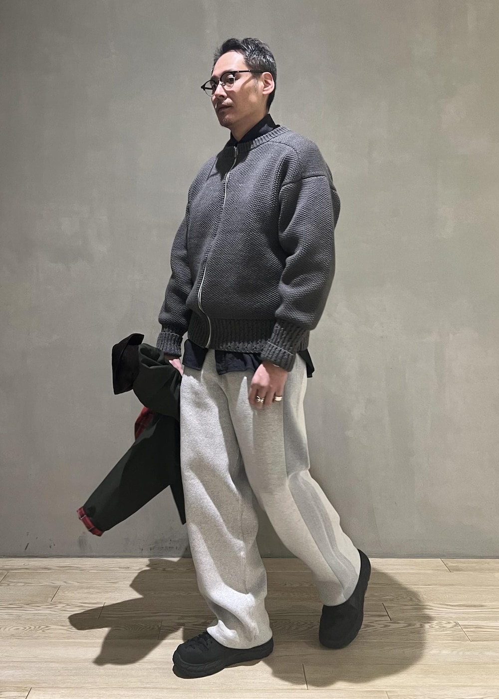 グリーン系のブルゾン、グレー系のその他パンツ、グレー系のカーディガン/ボレロを着用したメンズの冬コーディネートの10枚目の写真