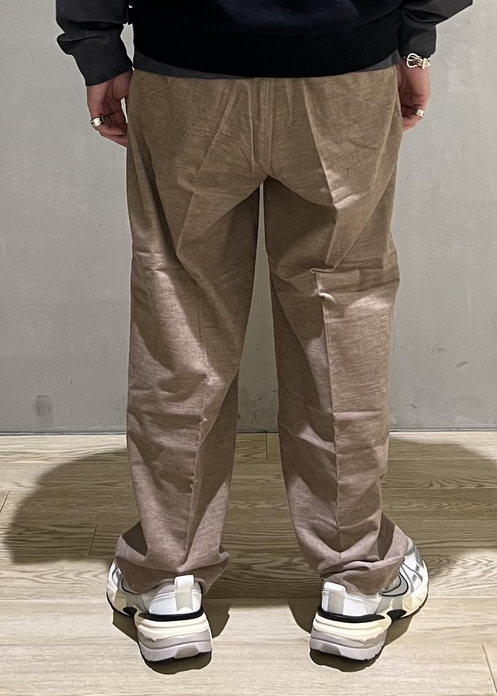 ベージュ系のスラックス、グレー系のTシャツ/カットソー、ホワイト系のスニーカーを着用したメンズの秋コーディネートの9枚目の写真