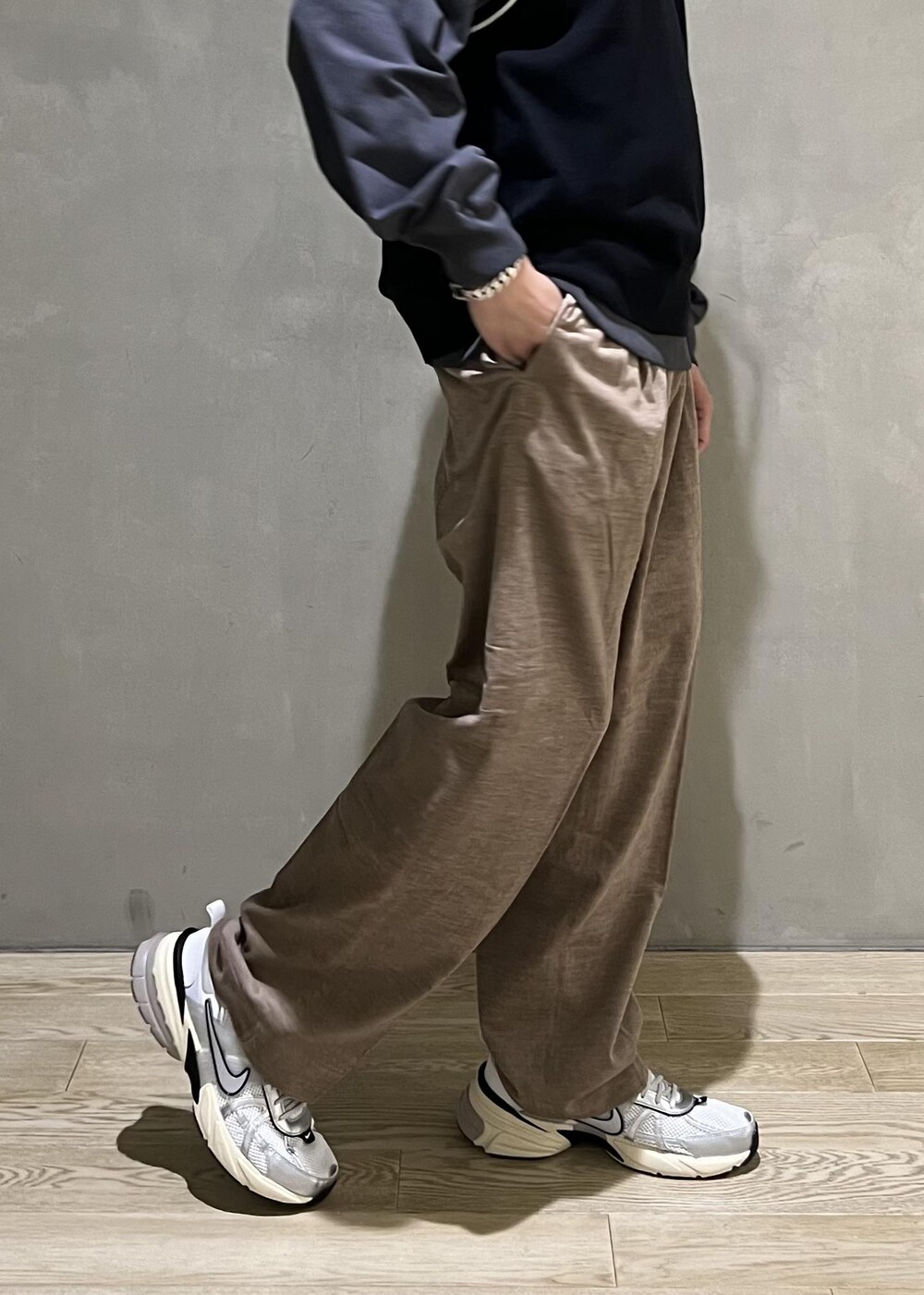 ベージュ系のスラックス、グレー系のTシャツ/カットソー、ホワイト系のスニーカーを着用したメンズの秋コーディネートの8枚目の写真