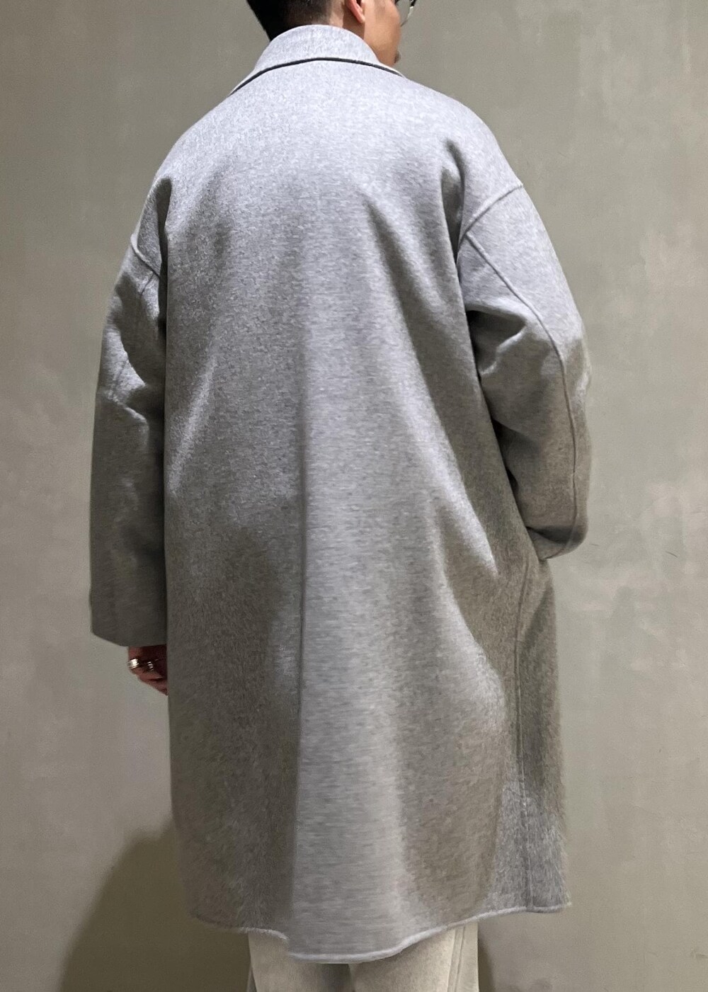 グレー系のステンカラーコート、グレー系のその他パンツ、ブラック系のショルダーバッグを着用したメンズの冬コーディネートの6枚目の写真