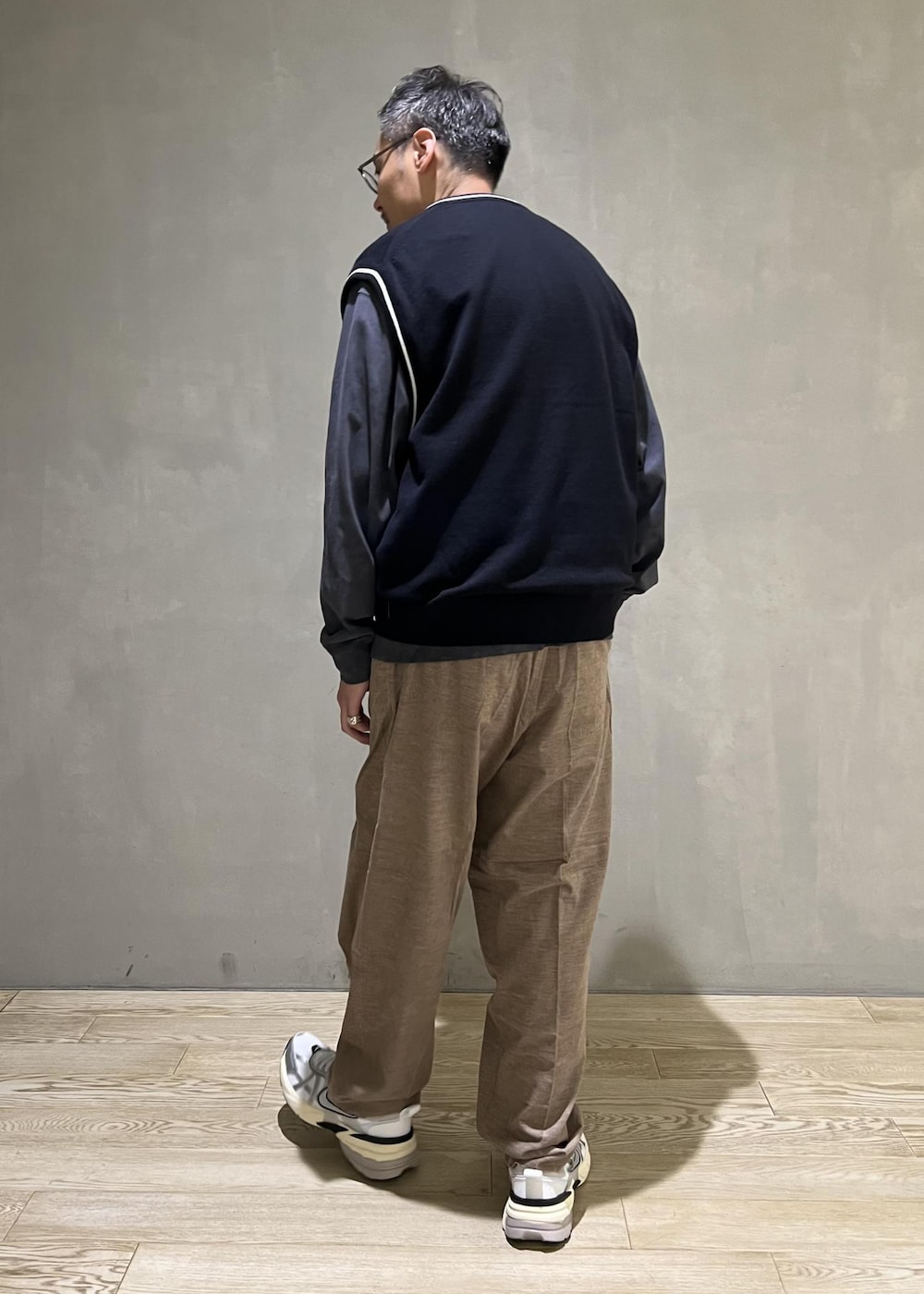 ベージュ系のスラックス、グレー系のTシャツ/カットソー、ホワイト系のスニーカーを着用したメンズの秋コーディネートの3枚目の写真