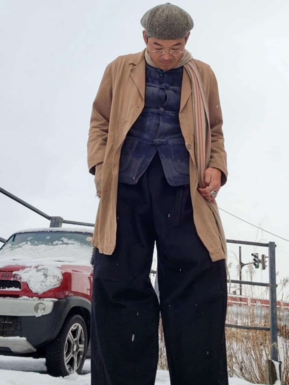 グレー系のノーカラージャケット、ブラウン系のステンカラーコート、ブラック系のその他パンツを着用したメンズの冬コーディネートの2枚目の写真