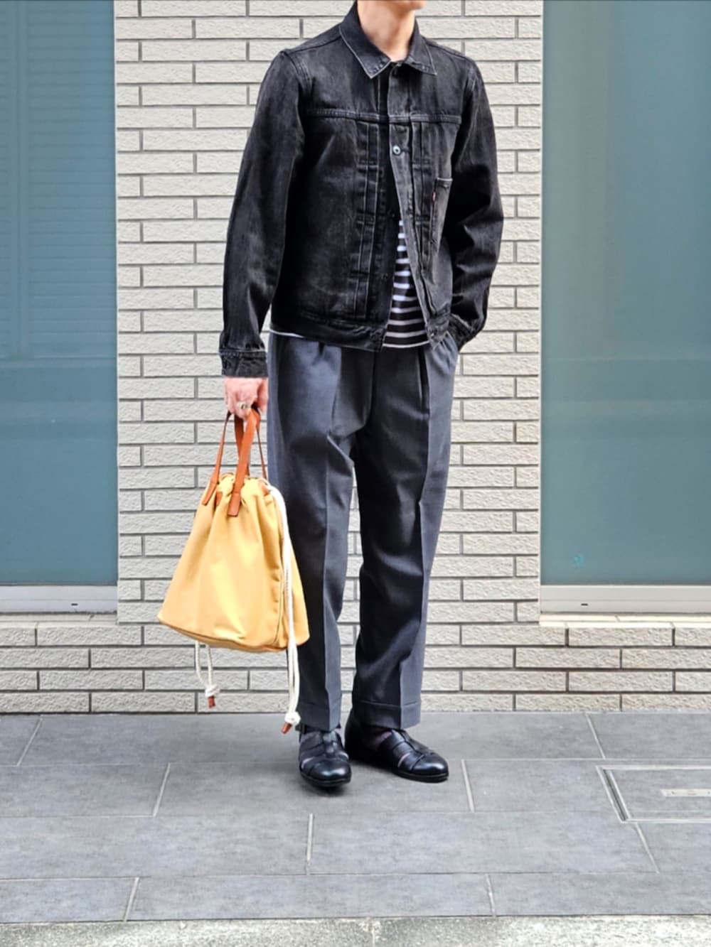 ブラック系のデニムジャケット、グレー系のTシャツ/カットソー、グレー系のスラックスを着用したメンズの秋コーディネートの2枚目の写真