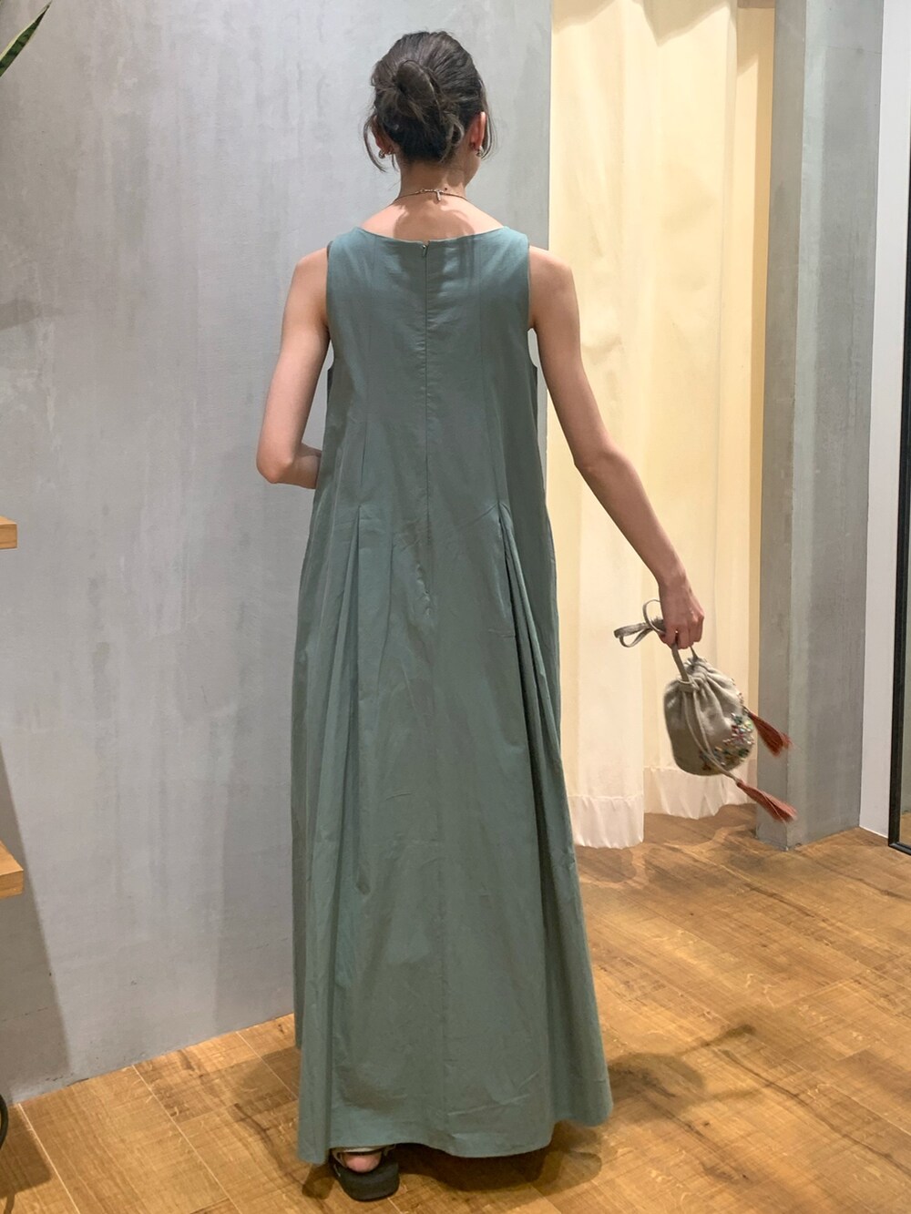 ブラック系のハンドバッグ、グリーン系のワンピース、シルバー系のイヤリングを着用したレディースの夏コーディネートの3枚目の写真