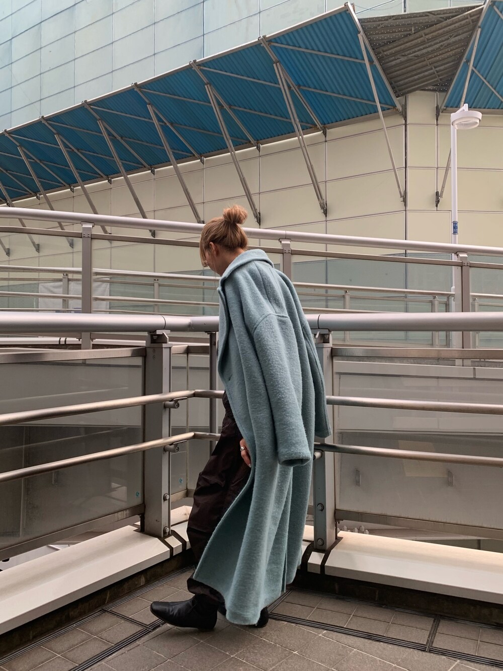 ブルー系のチェスターコート、ブラック系のブーツ、ブラック系のTシャツ/カットソーを着用したレディースの冬コーディネートの2枚目の写真