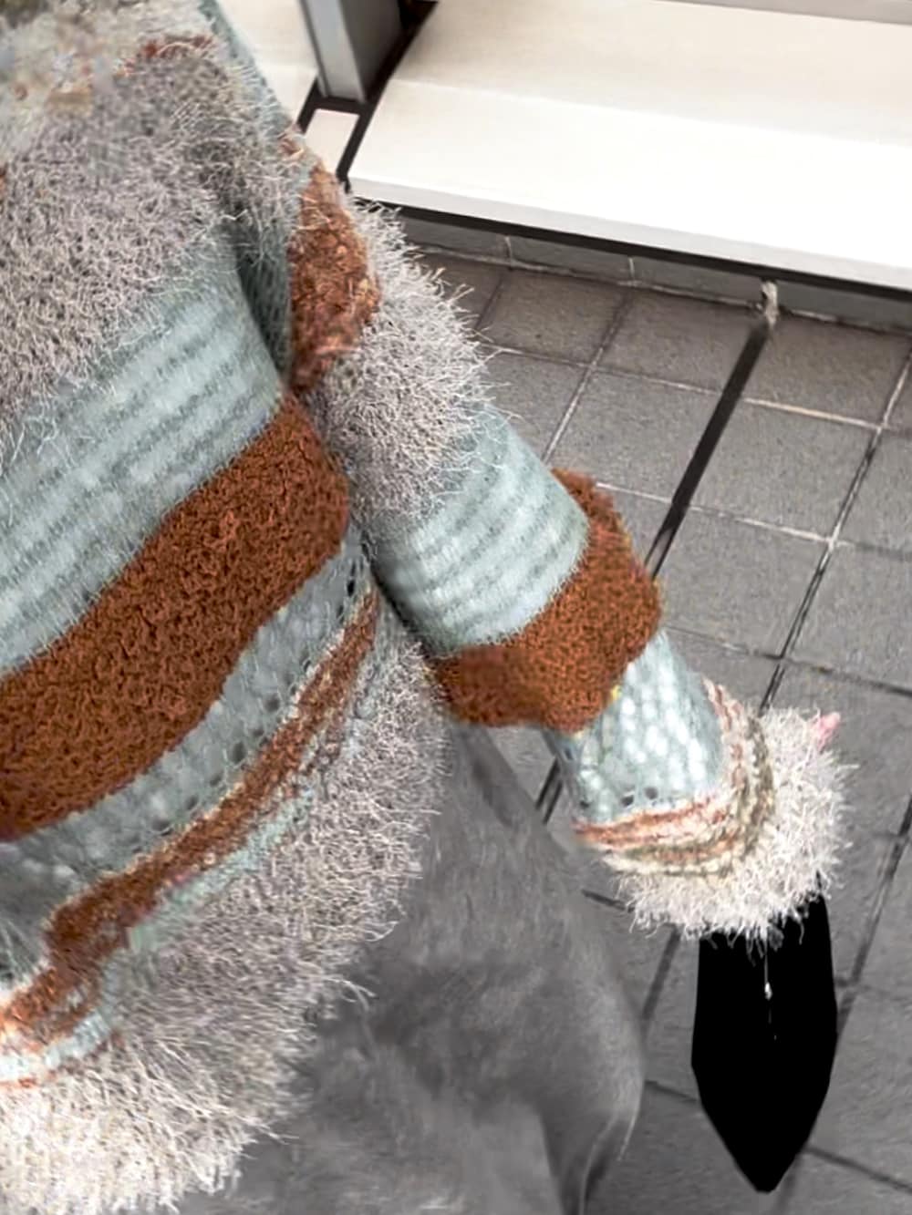 ブルー系のニット/セーター、グレー系のスカート、ブラック系のハンドバッグを着用したレディースの秋コーディネートの4枚目の写真