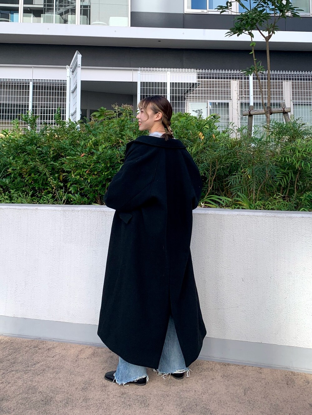 ブルー系のニット/セーター、ブラック系のチェスターコート、ブルー系のデニムパンツを着用したレディースの秋コーディネートの3枚目の写真