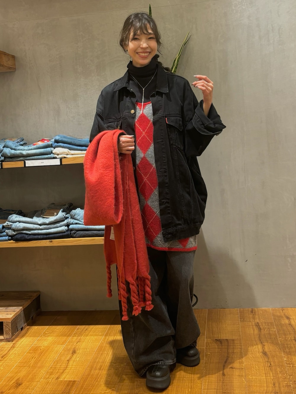 ブラック系のデニムジャケット、レッド系のニット/セーター、ブラック系のデニムパンツを着用したレディースの秋コーディネートの4枚目の写真
