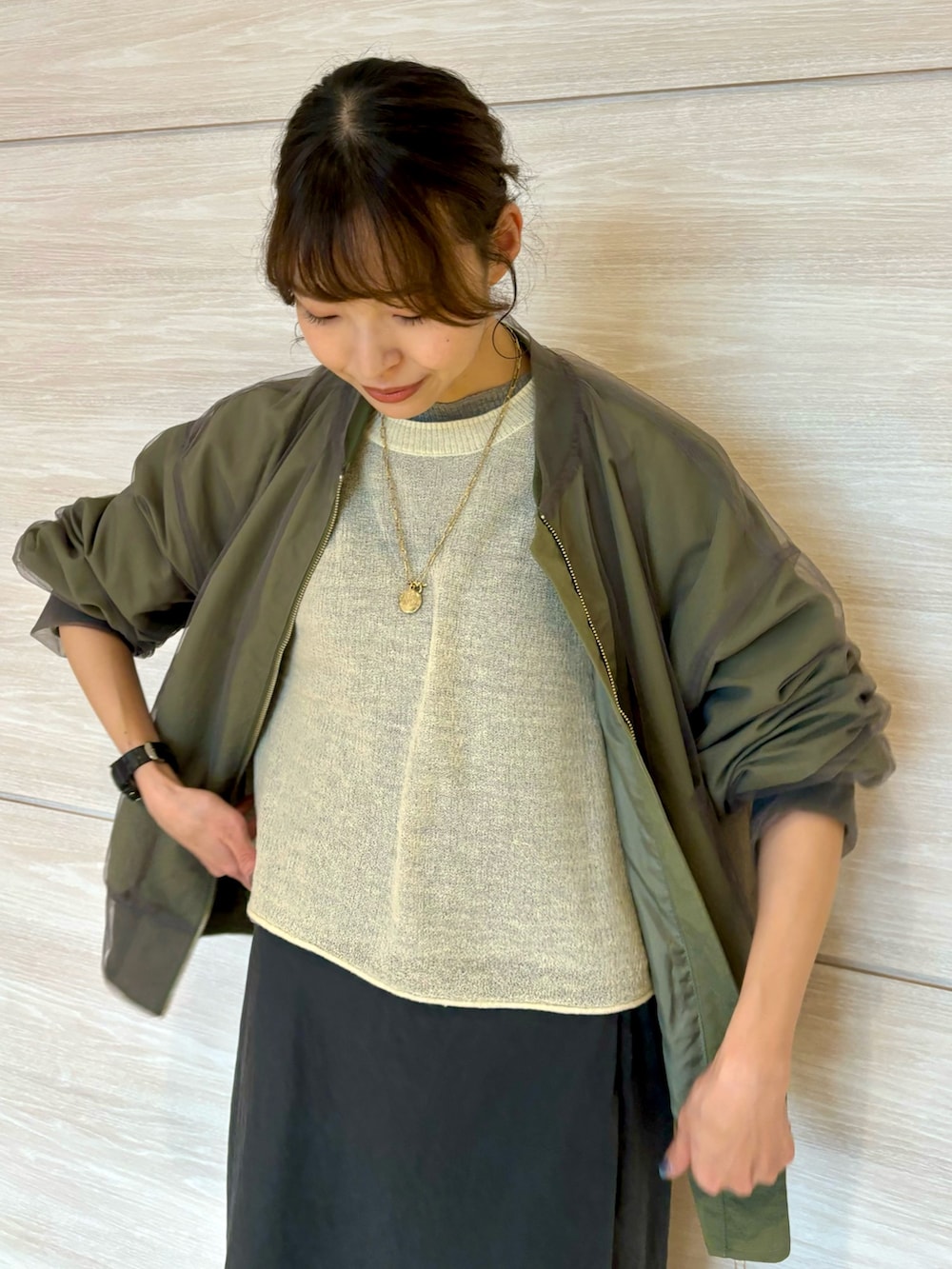 イエロー系のニット/セーター、グレー系のスカート、グリーン系のMA-1を着用したレディースの秋コーディネートの4枚目の写真