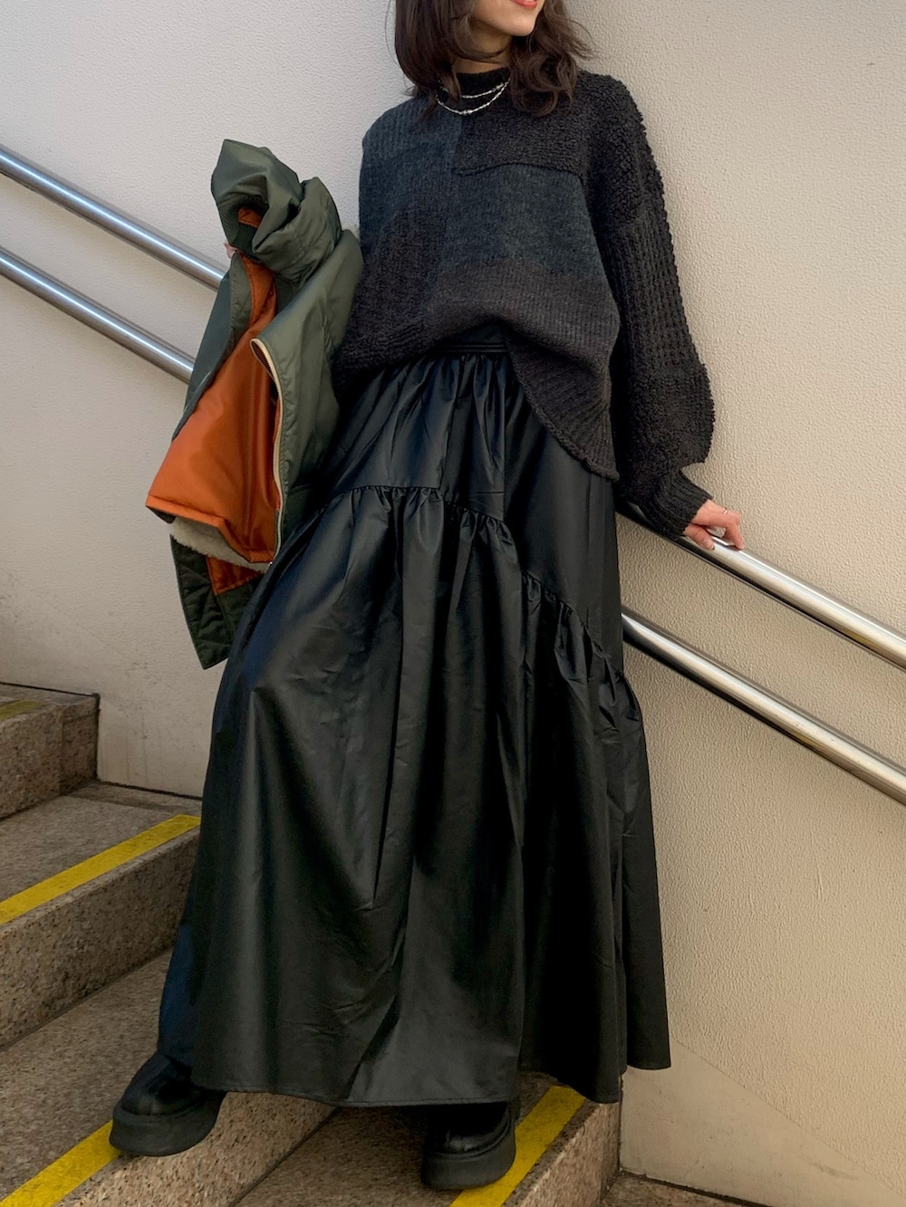 ブラック系のスカート、ブラック系のブーツ、グレー系のニット/セーターを着用したレディースの冬コーディネートの3枚目の写真