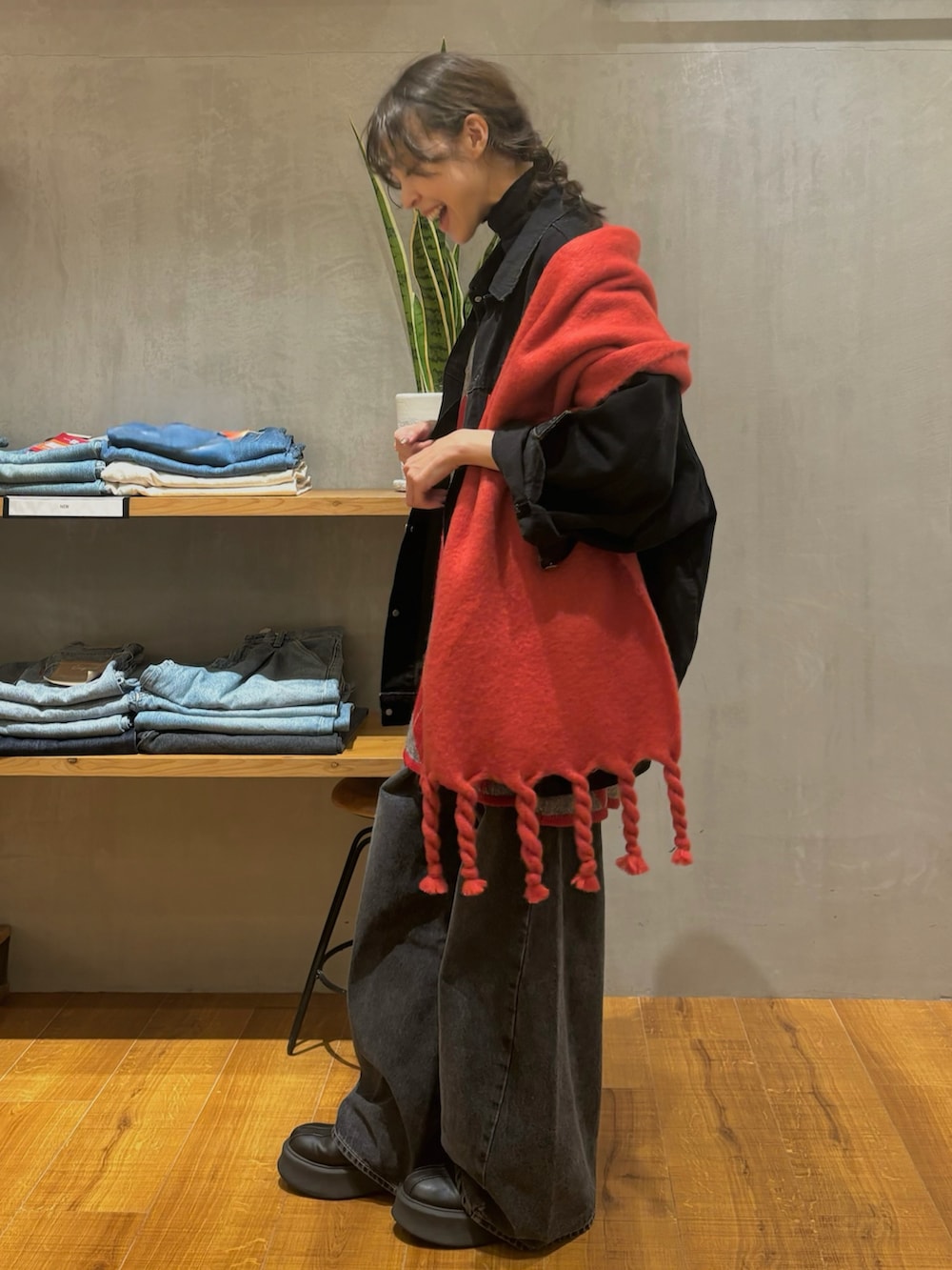 ブラック系のデニムジャケット、レッド系のニット/セーター、ブラック系のデニムパンツを着用したレディースの秋コーディネートの2枚目の写真