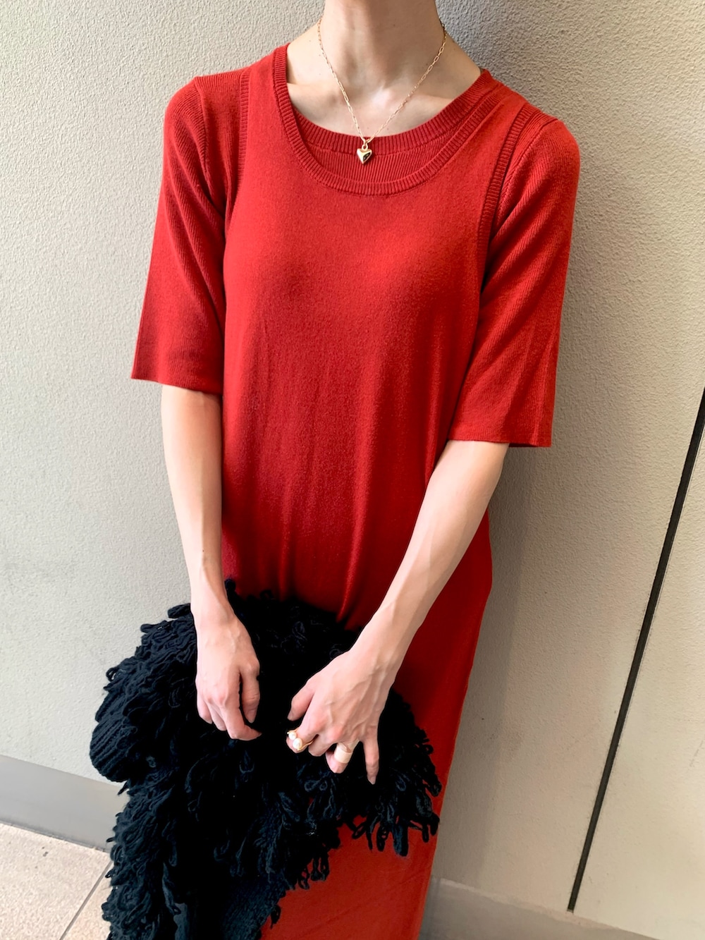 レッド系のワンピース、ブラック系のベスト、ブラック系のブーツを着用したレディースの秋コーディネートの7枚目の写真