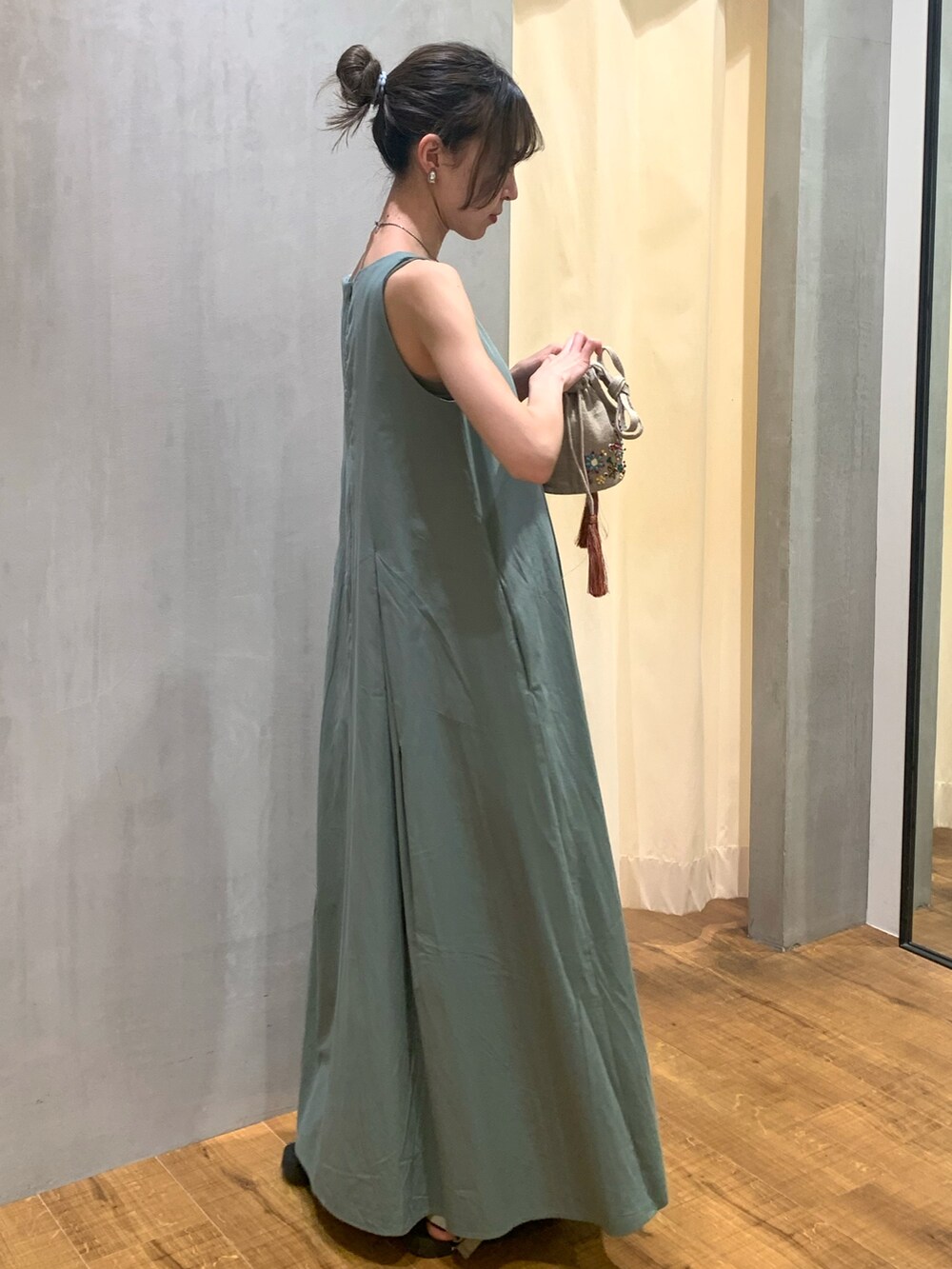 ブラック系のハンドバッグ、グリーン系のワンピース、シルバー系のイヤリングを着用したレディースの夏コーディネートの2枚目の写真