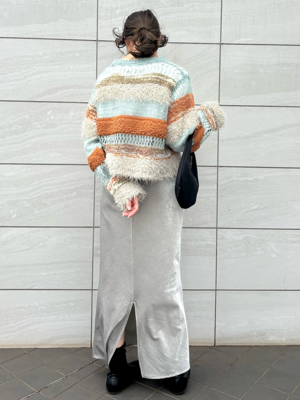 ブルー系のニット/セーター、グレー系のスカート、ブラック系のハンドバッグを着用したレディースの秋コーディネートの3枚目の写真