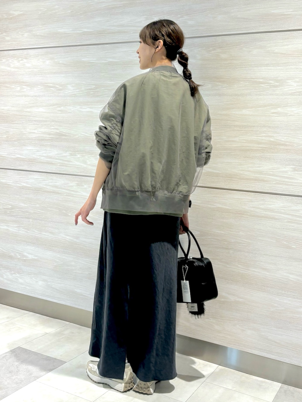 イエロー系のニット/セーター、グレー系のスカート、グリーン系のMA-1を着用したレディースの秋コーディネートの3枚目の写真