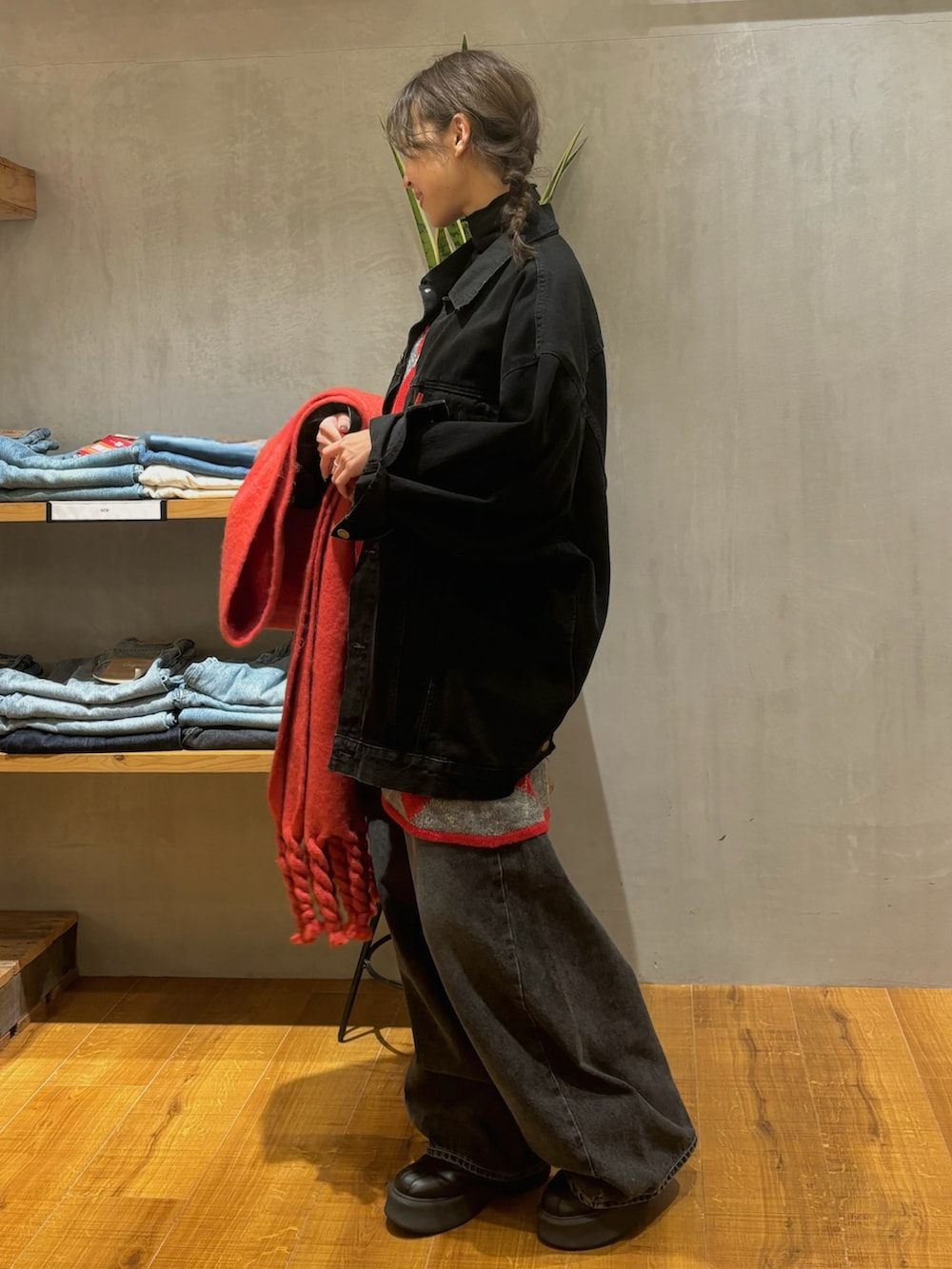 ブラック系のデニムジャケット、レッド系のニット/セーター、ブラック系のデニムパンツを着用したレディースの秋コーディネートの5枚目の写真