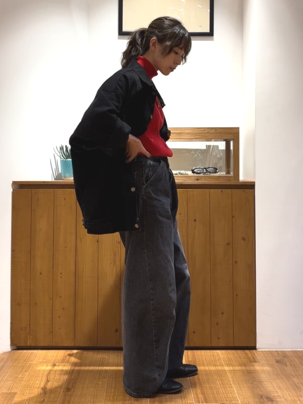 ブラック系のデニムパンツ、ブラック系のデニムジャケット、レッド系のニット/セーターを着用したレディースの秋コーディネートの2枚目の写真