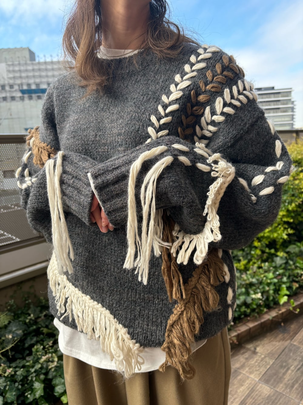 ベージュ系のその他パンツ、ホワイト系のTシャツ/カットソー、グレー系のニット/セーターを着用したレディースの冬コーディネートの4枚目の写真