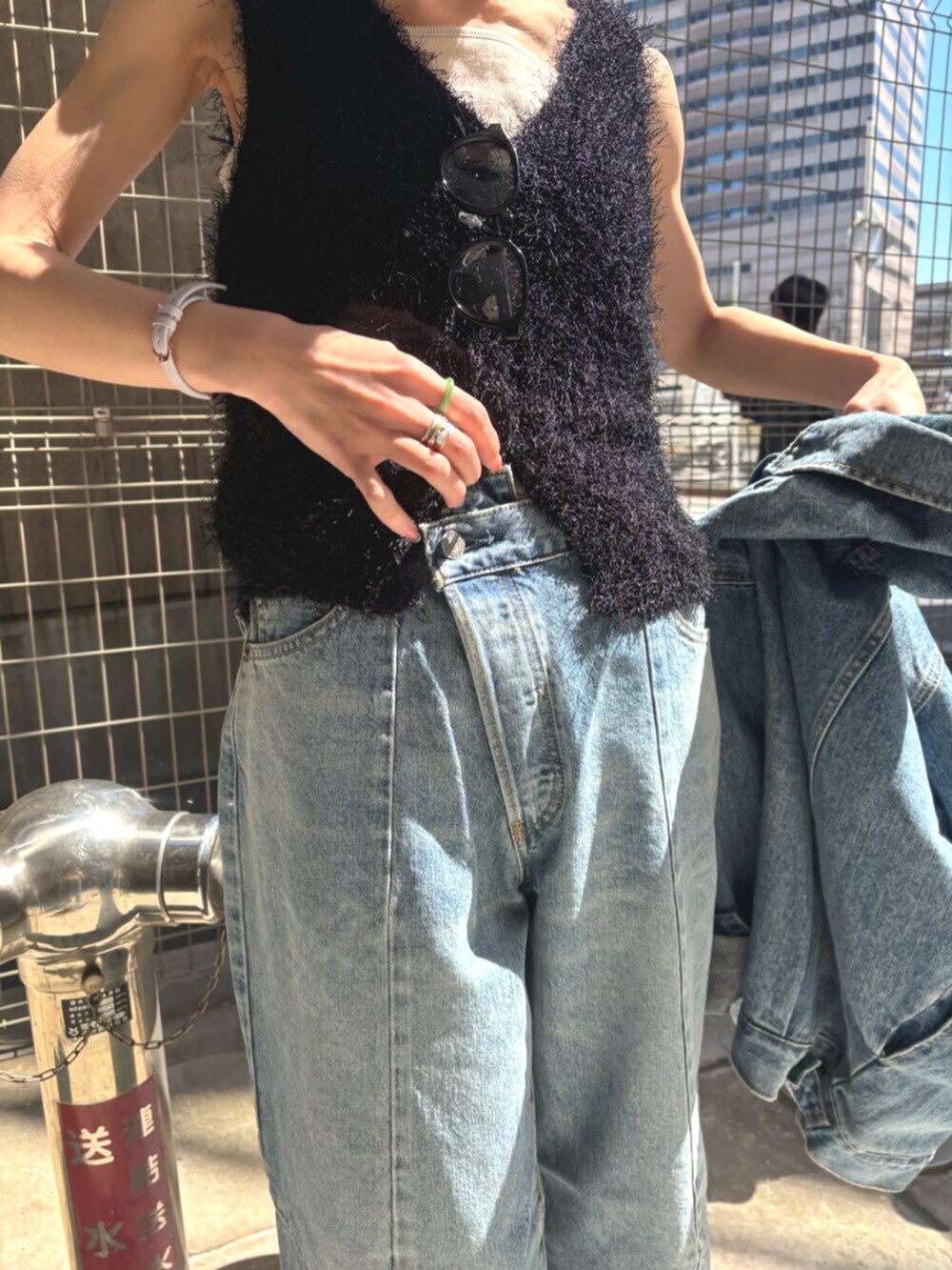 ブラック系のパンプス、ブラック系のベスト、ブルー系のデニムジャケットを着用したレディースの春コーディネートの5枚目の写真