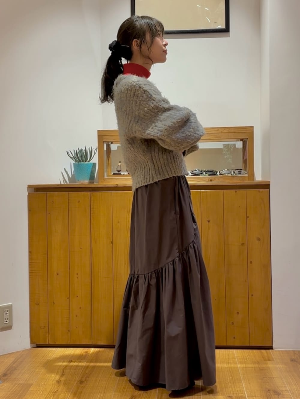 グレー系のスカート、グレー系のニット/セーター、レッド系のニット/セーターを着用したレディースの秋コーディネートの3枚目の写真