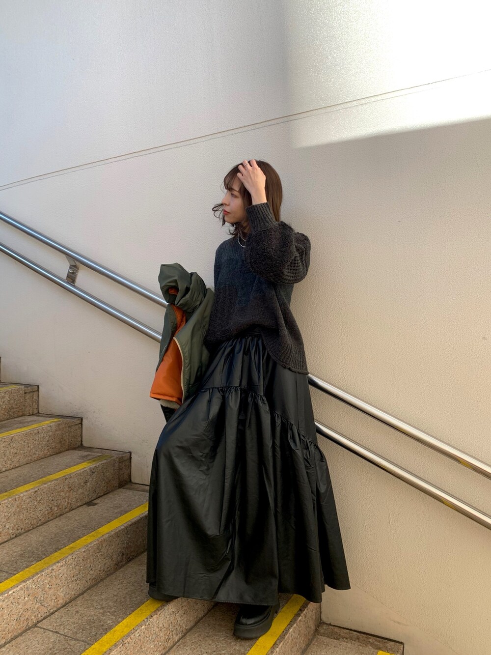 ブラック系のスカート、ブラック系のブーツ、グレー系のニット/セーターを着用したレディースの冬コーディネートの2枚目の写真