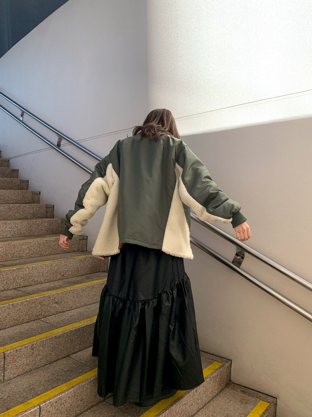 ブラック系のスカート、ブラック系のブーツ、グレー系のニット/セーターを着用したレディースの冬コーディネートの5枚目の写真