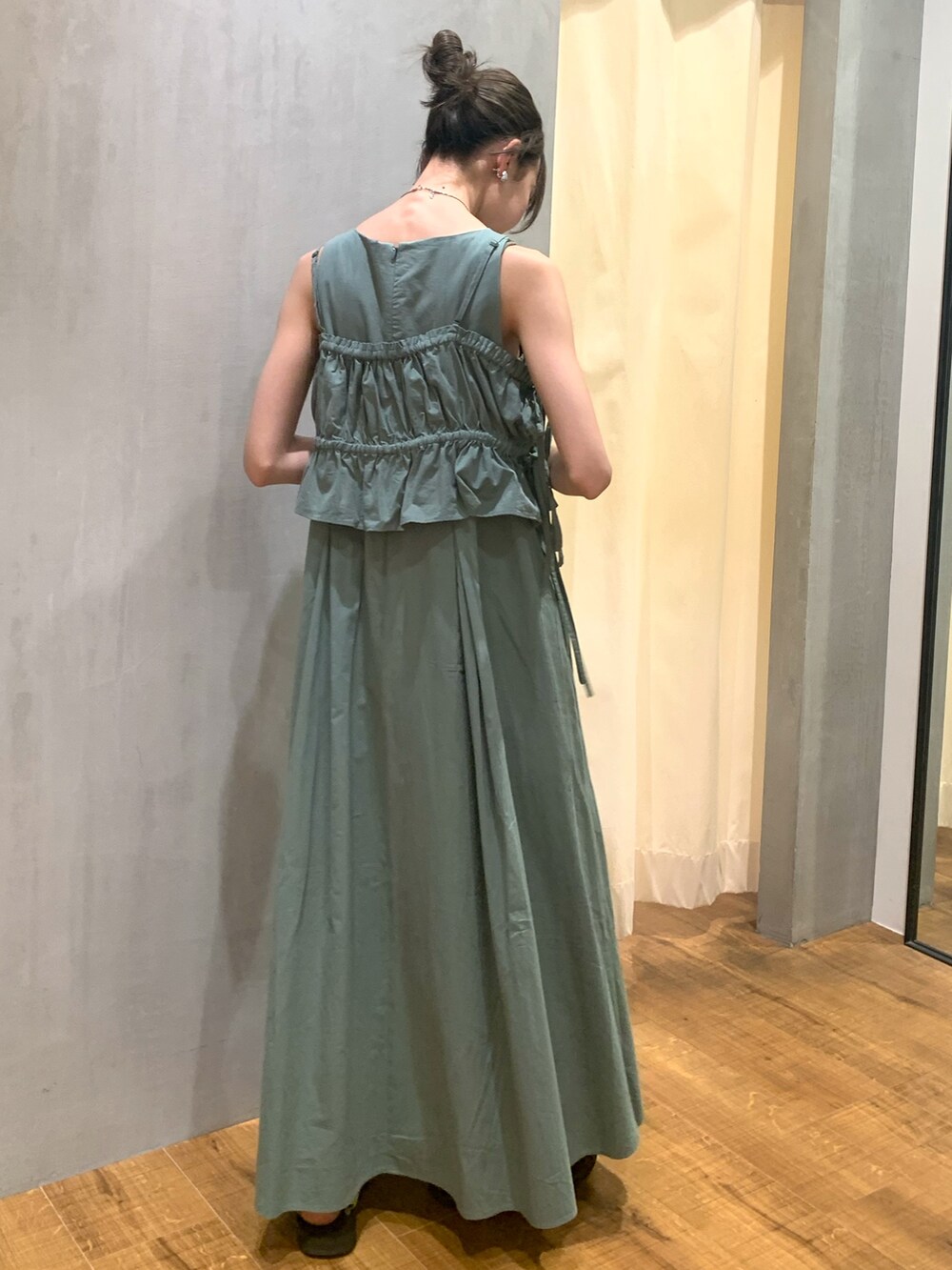 グリーン系のワンピース、ゴールド系のネックレス、シルバー系のイヤリングを着用したレディースの夏コーディネートの3枚目の写真