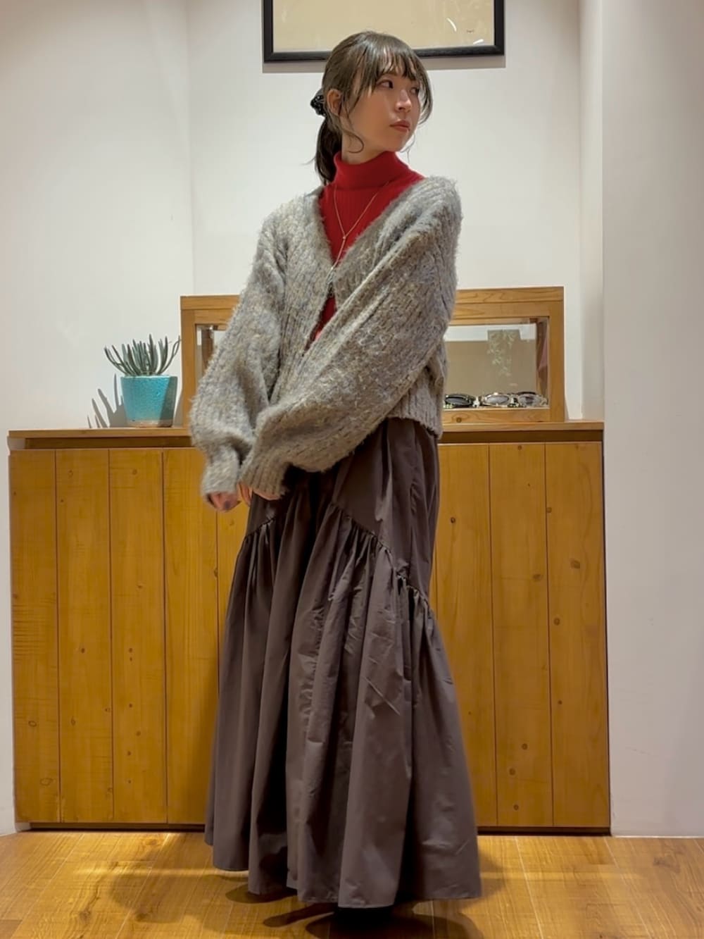 グレー系のスカート、グレー系のニット/セーター、レッド系のニット/セーターを着用したレディースの秋コーディネートの2枚目の写真