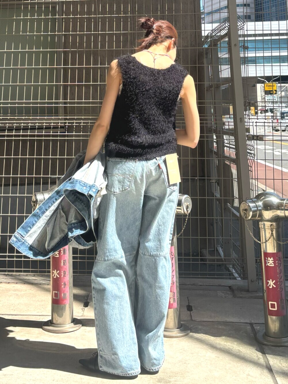 ブラック系のパンプス、ブラック系のベスト、ブルー系のデニムジャケットを着用したレディースの春コーディネートの3枚目の写真