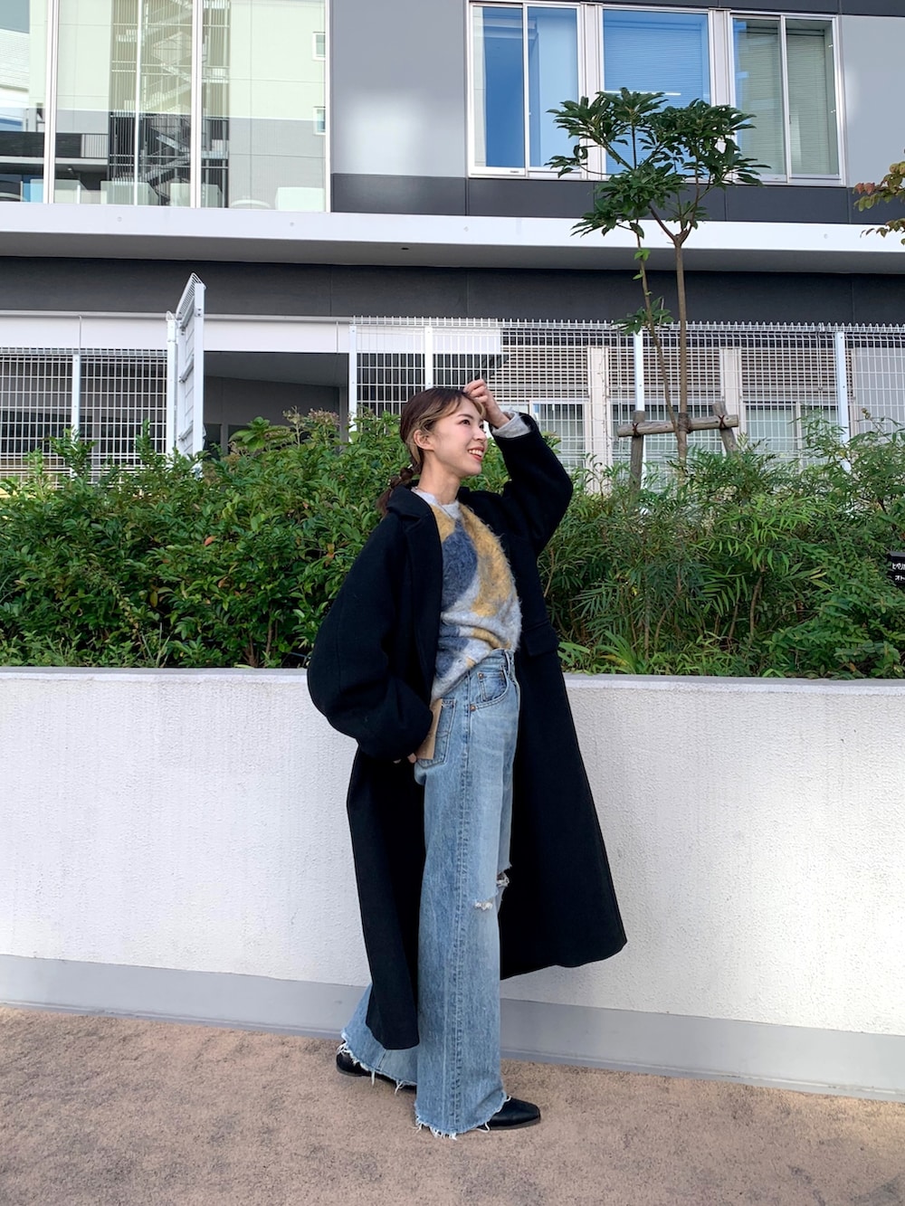 ブルー系のニット/セーター、ブラック系のチェスターコート、ブルー系のデニムパンツを着用したレディースの秋コーディネートの2枚目の写真