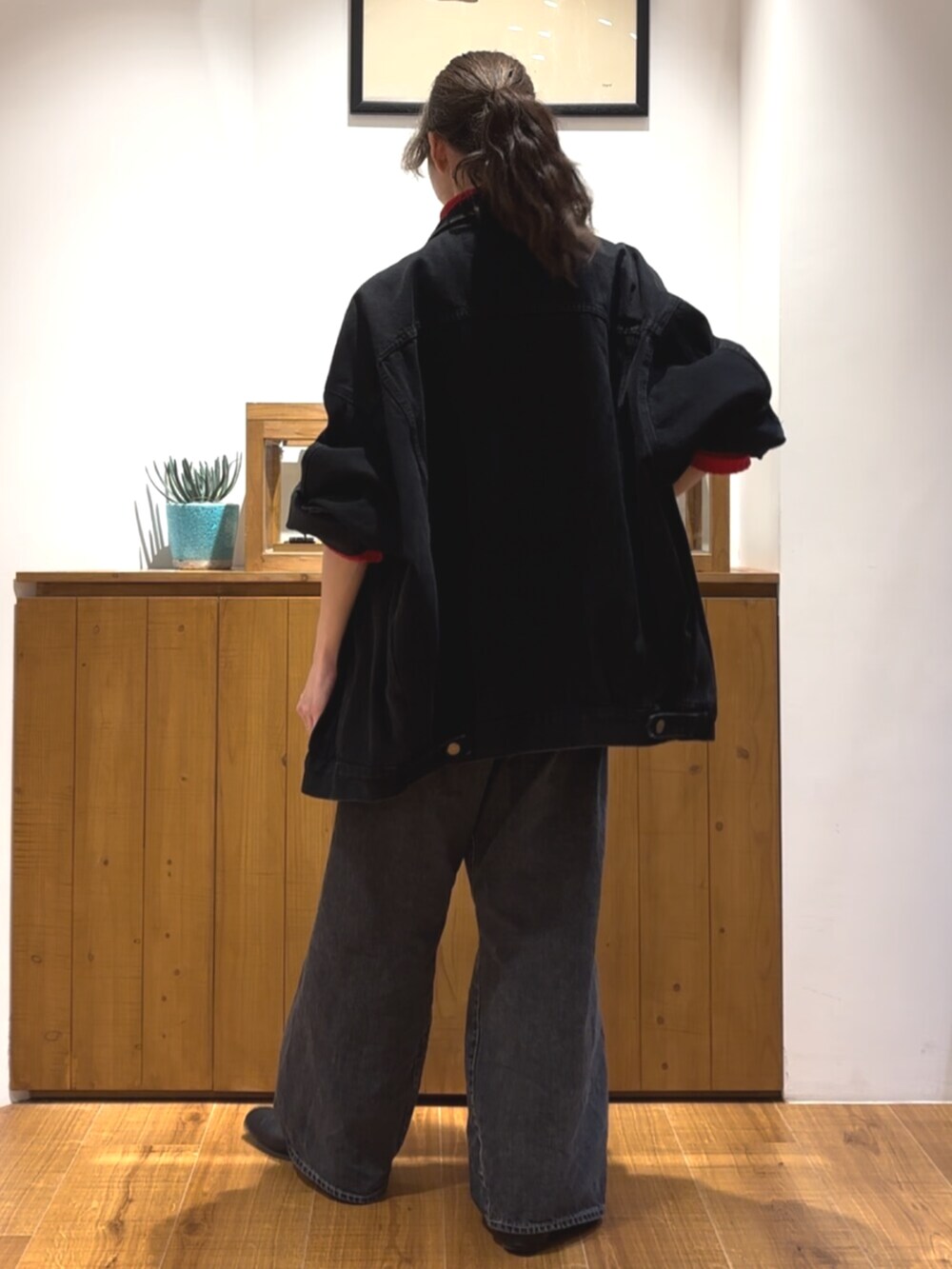 ブラック系のデニムパンツ、ブラック系のデニムジャケット、レッド系のニット/セーターを着用したレディースの秋コーディネートの3枚目の写真