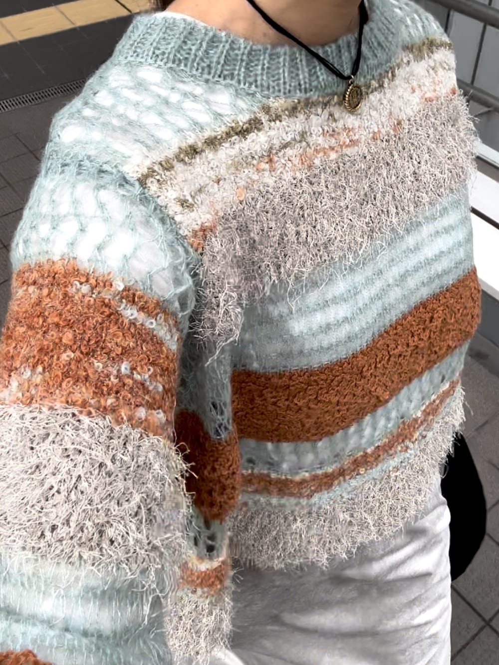 ブルー系のニット/セーター、グレー系のスカート、ブラック系のハンドバッグを着用したレディースの秋コーディネートの5枚目の写真